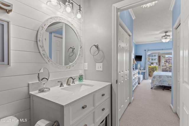 bathroom featuring vanity, a textured ceiling, ceiling fan, and wood walls