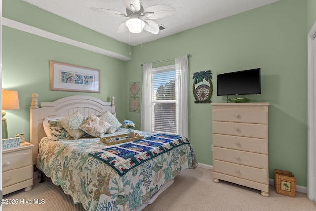 bedroom featuring ceiling fan, light colored carpet, and a textured ceiling