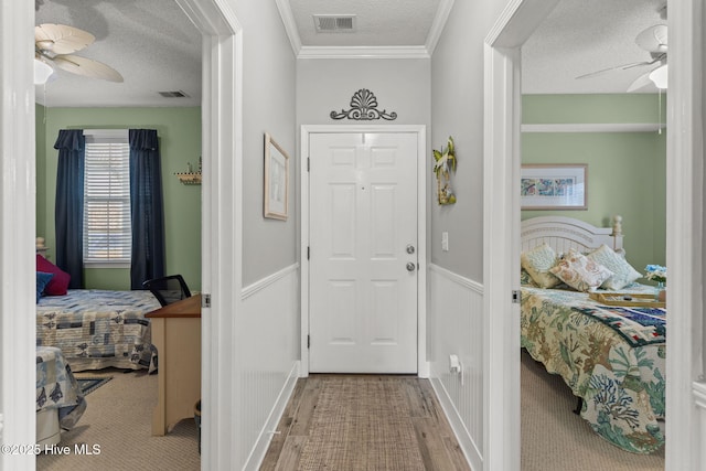 entryway with crown molding, wood-type flooring, a textured ceiling, and ceiling fan