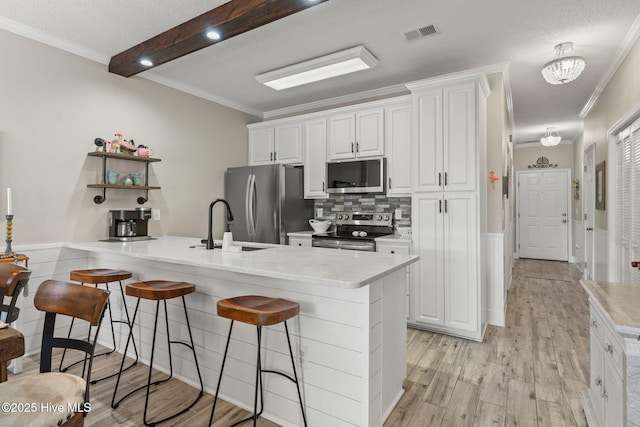 kitchen featuring white cabinetry, sink, light wood-type flooring, stainless steel appliances, and a textured ceiling