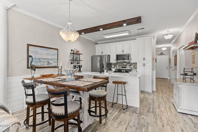 kitchen featuring sink, appliances with stainless steel finishes, white cabinets, decorative backsplash, and light wood-type flooring