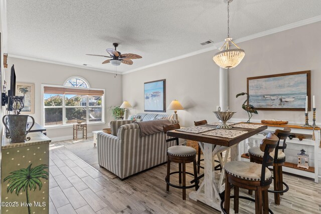 living room featuring ceiling fan, ornamental molding, light hardwood / wood-style floors, and decorative columns