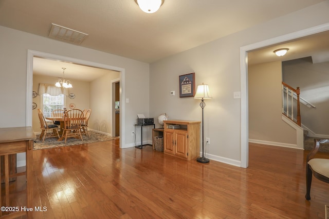 interior space featuring baseboards, visible vents, stairway, and wood finished floors