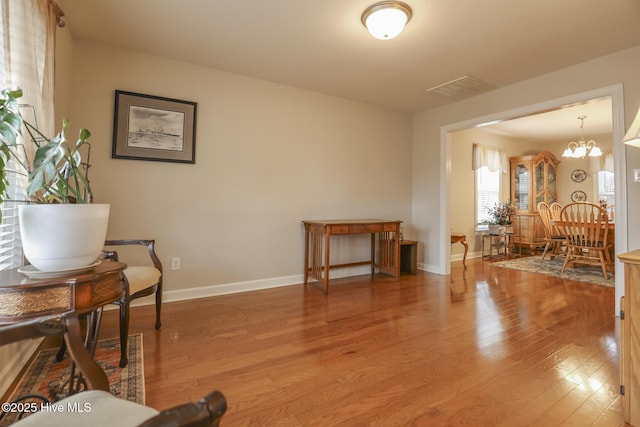 sitting room featuring light wood finished floors, visible vents, baseboards, and an inviting chandelier