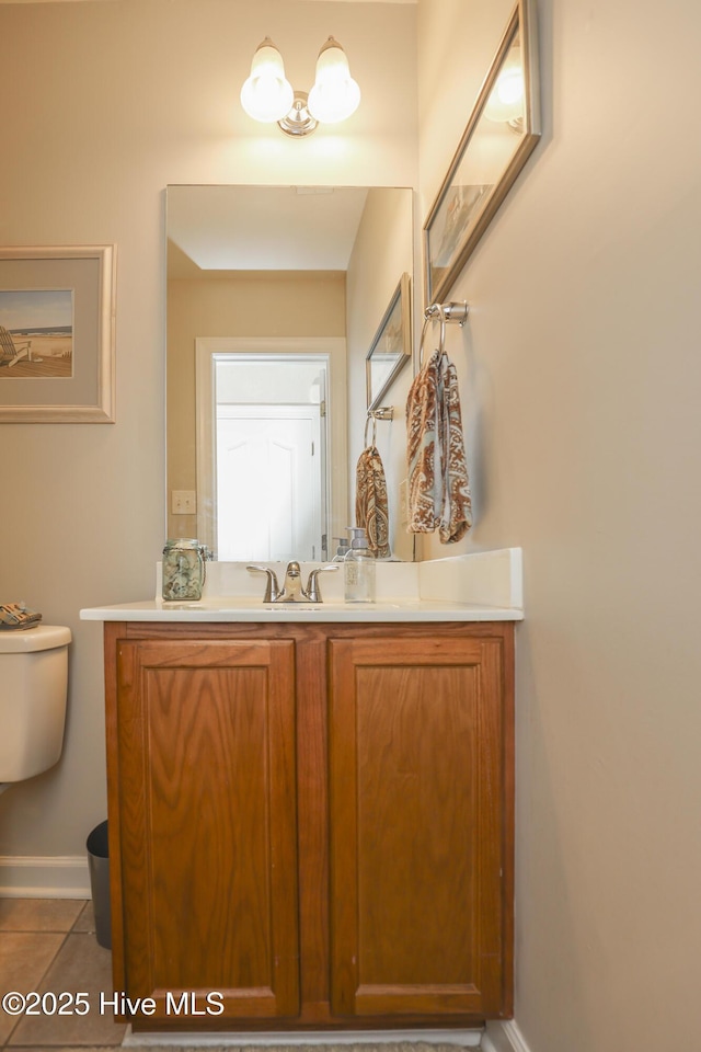 bathroom with tile patterned flooring, baseboards, vanity, and toilet