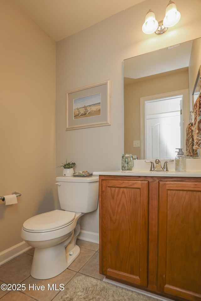 bathroom featuring toilet, vanity, baseboards, and tile patterned floors