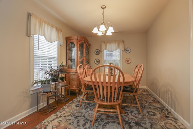 dining area with baseboards, visible vents, a chandelier, and dark wood-style flooring