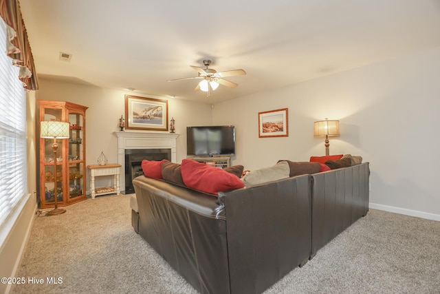 living area featuring a fireplace, visible vents, light carpet, ceiling fan, and baseboards