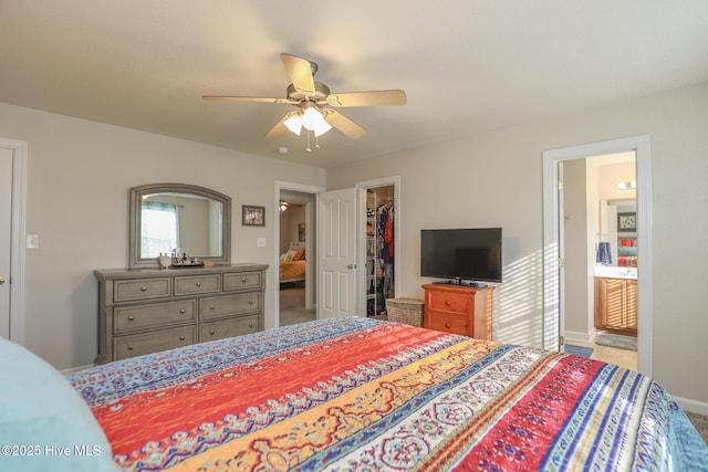 carpeted bedroom featuring a walk in closet, a closet, a ceiling fan, connected bathroom, and baseboards