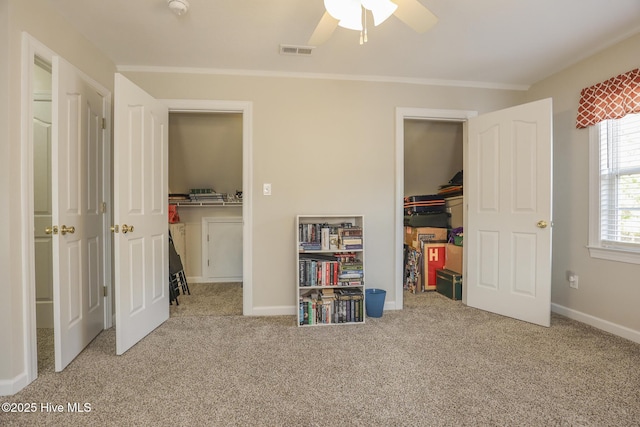 unfurnished bedroom featuring baseboards, visible vents, ornamental molding, a spacious closet, and carpet floors