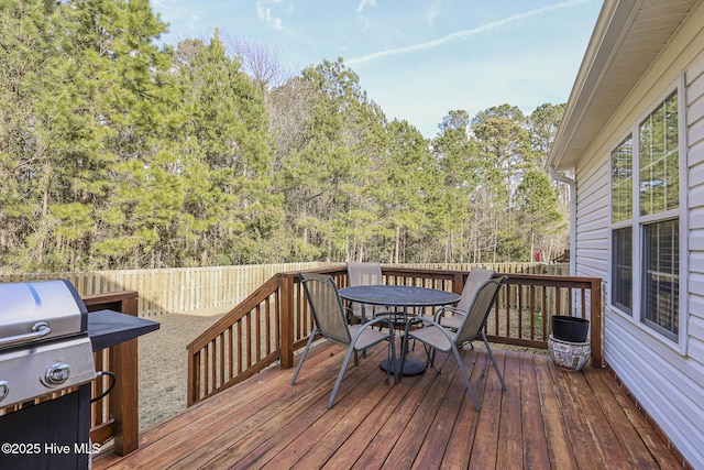 wooden deck featuring a fenced backyard, outdoor dining area, and grilling area