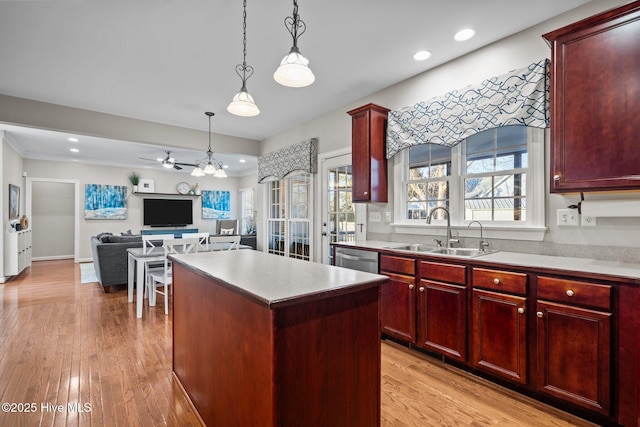 kitchen featuring hanging light fixtures, a center island, sink, and light wood-type flooring