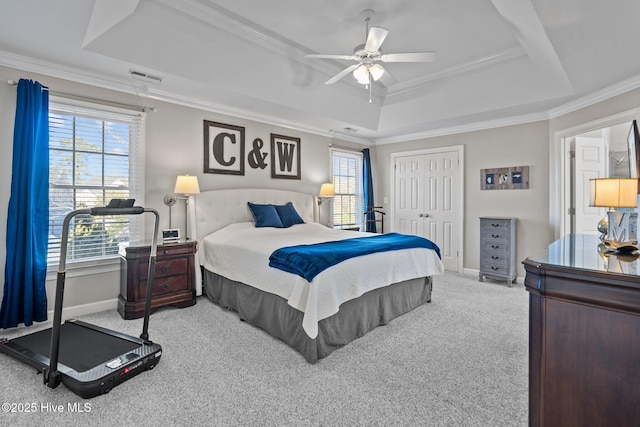 bedroom with crown molding, a closet, a tray ceiling, and light carpet