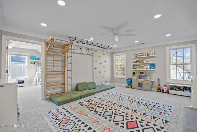 recreation room featuring carpet floors, ornamental molding, a healthy amount of sunlight, and ceiling fan