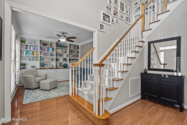 stairway featuring hardwood / wood-style flooring, ceiling fan, and ornamental molding