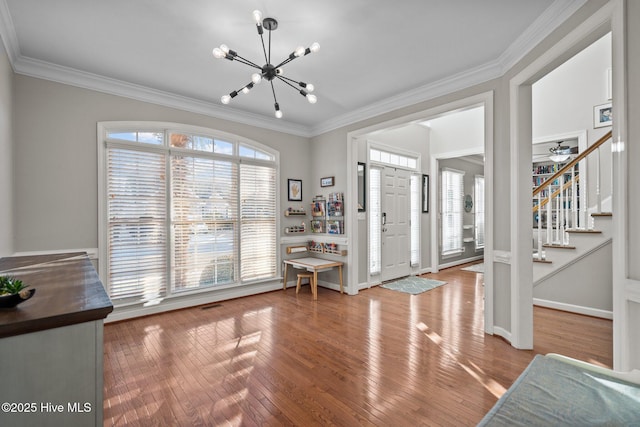 entryway featuring crown molding, hardwood / wood-style floors, and a notable chandelier