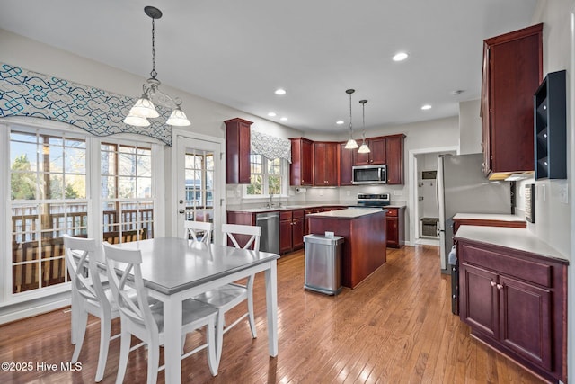 kitchen featuring stainless steel appliances, a center island, light hardwood / wood-style floors, and hanging light fixtures