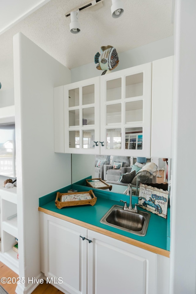 bar with sink, a textured ceiling, and white cabinets