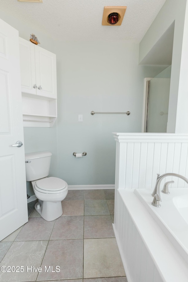 bathroom featuring tile patterned flooring, toilet, and a textured ceiling