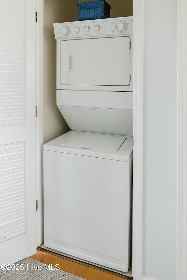 laundry area with stacked washing maching and dryer and light hardwood / wood-style flooring