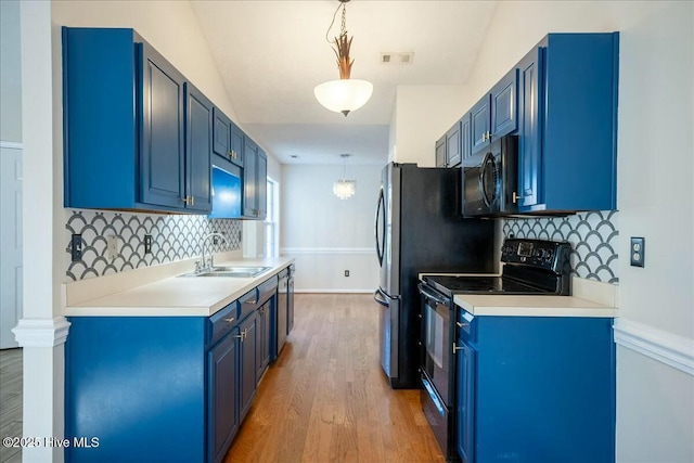 kitchen featuring sink, black appliances, hanging light fixtures, and blue cabinetry