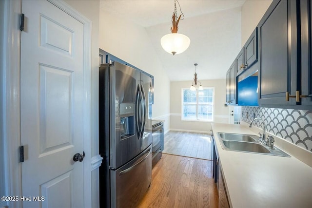 kitchen featuring decorative light fixtures, tasteful backsplash, sink, stainless steel fridge with ice dispenser, and light hardwood / wood-style flooring