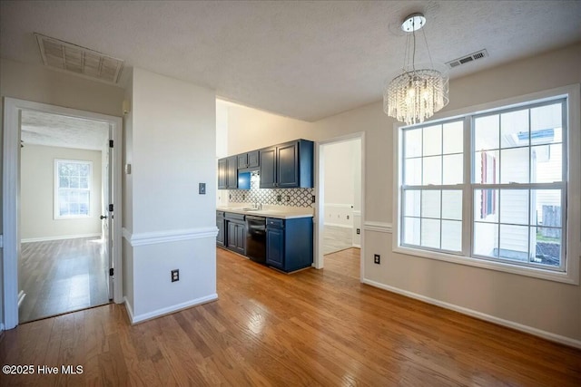 kitchen featuring decorative backsplash, decorative light fixtures, black dishwasher, and light hardwood / wood-style flooring