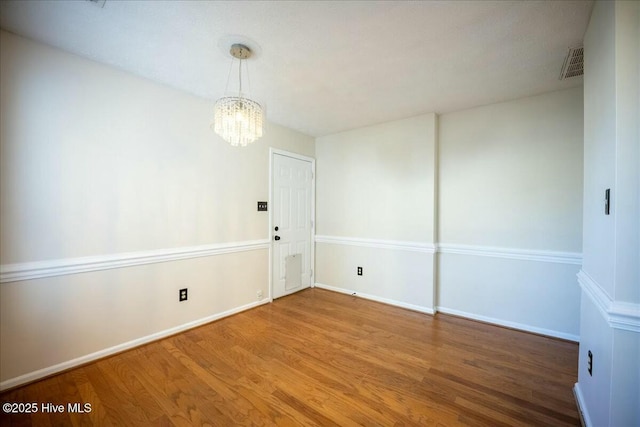 empty room featuring hardwood / wood-style floors and a chandelier