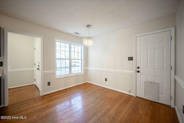 unfurnished dining area with an inviting chandelier and wood-type flooring