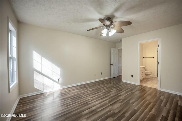 unfurnished bedroom featuring ensuite bathroom, a textured ceiling, and dark hardwood / wood-style flooring