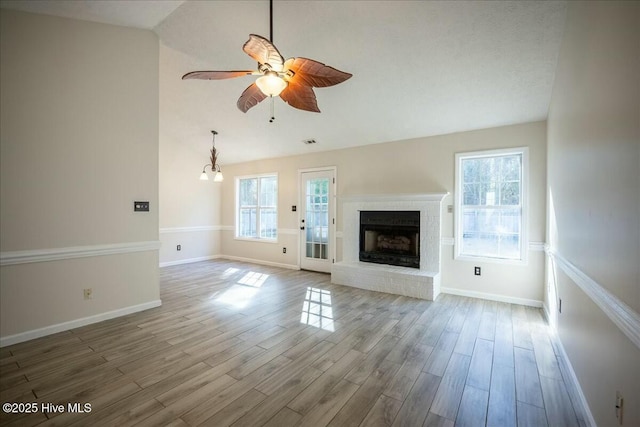 unfurnished living room featuring hardwood / wood-style flooring, ceiling fan, vaulted ceiling, and a brick fireplace