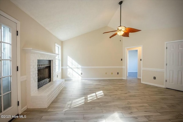 unfurnished living room featuring vaulted ceiling, ceiling fan, a fireplace, and light hardwood / wood-style flooring