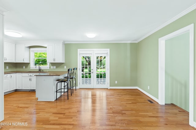 kitchen with white cabinetry, a kitchen breakfast bar, french doors, and a healthy amount of sunlight