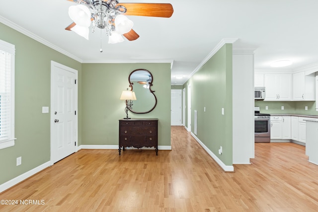 foyer entrance with crown molding, a wealth of natural light, ceiling fan, and light hardwood / wood-style flooring