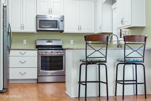 kitchen with stainless steel appliances, stone countertops, and white cabinets