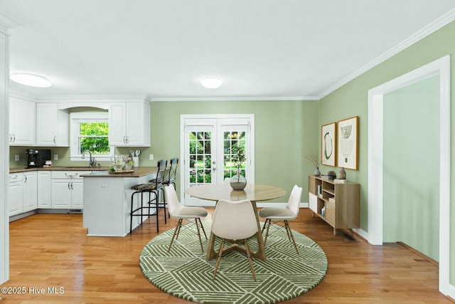 dining room featuring french doors, crown molding, and light wood-type flooring