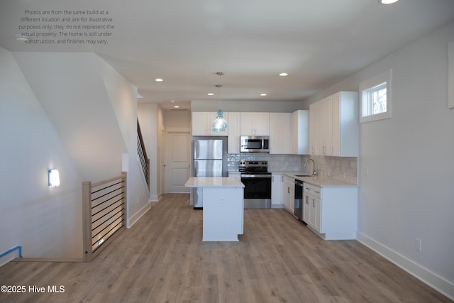 kitchen with white cabinetry, a kitchen island, pendant lighting, stainless steel appliances, and backsplash