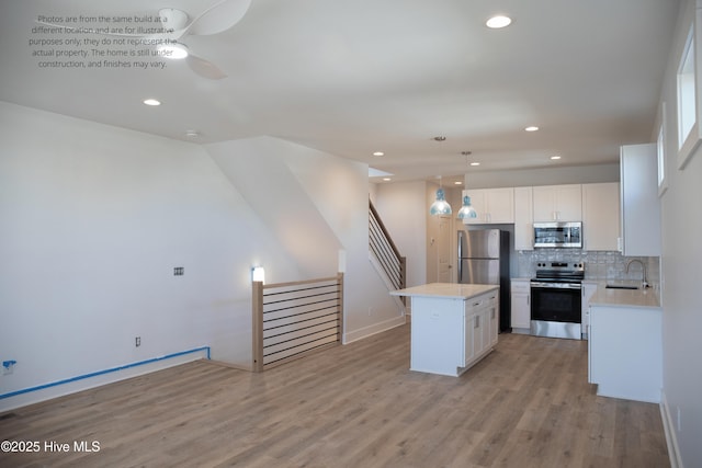 kitchen with pendant lighting, a kitchen island, white cabinets, and appliances with stainless steel finishes