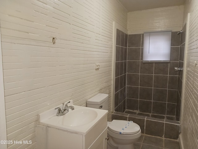 bathroom with vanity, toilet, and a tile shower