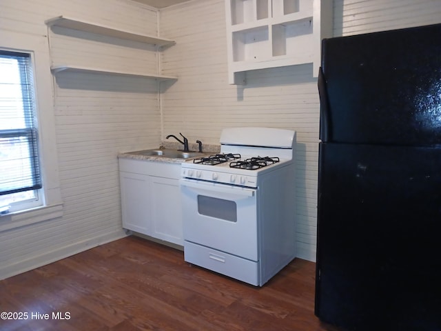 kitchen with sink, white cabinets, white range with gas cooktop, black fridge, and dark wood-type flooring