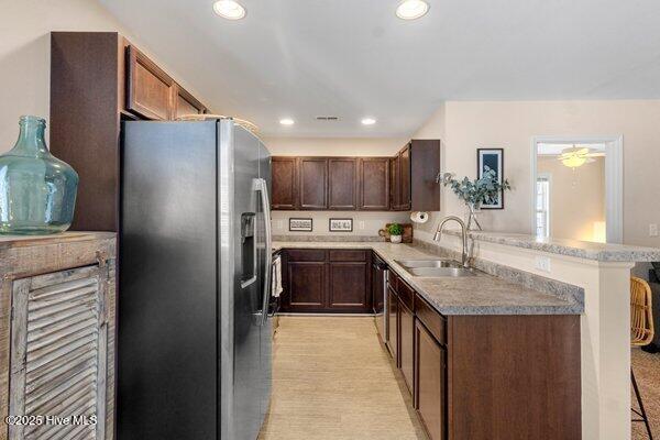 kitchen featuring stainless steel fridge with ice dispenser, dark brown cabinets, sink, and kitchen peninsula