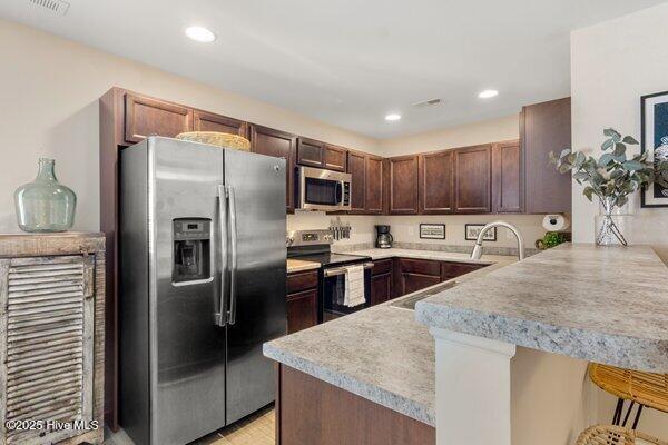 kitchen featuring appliances with stainless steel finishes, sink, a kitchen bar, and kitchen peninsula