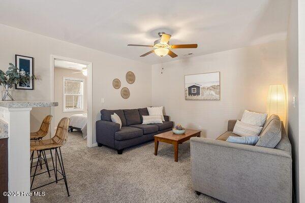 carpeted living room with ceiling fan