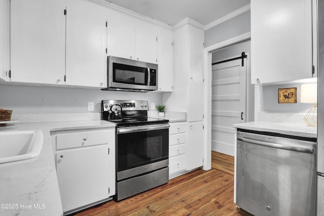 kitchen with white cabinetry, dark hardwood / wood-style flooring, stainless steel appliances, and a barn door