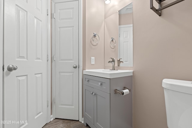 bathroom with vanity, toilet, and hardwood / wood-style floors