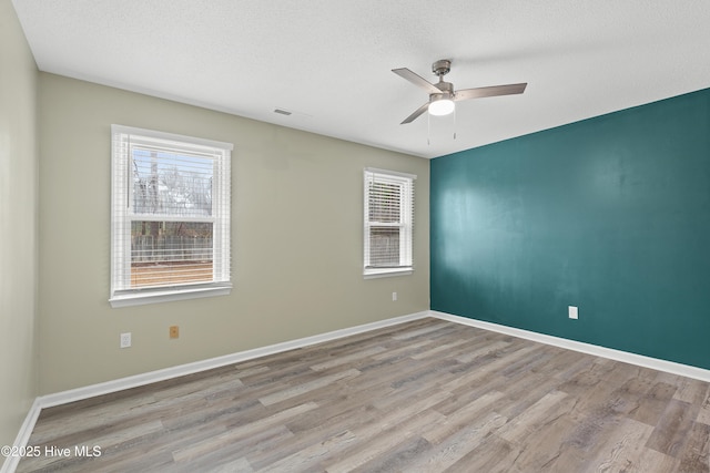 unfurnished room with ceiling fan, light hardwood / wood-style floors, and a textured ceiling