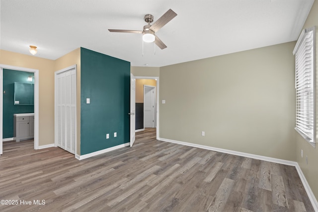 unfurnished bedroom with connected bathroom, a closet, ceiling fan, and light wood-type flooring