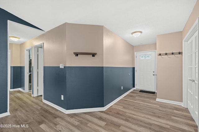 corridor featuring wood-type flooring and vaulted ceiling