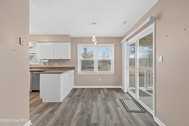 kitchen featuring pendant lighting, white cabinetry, plenty of natural light, and hardwood / wood-style flooring