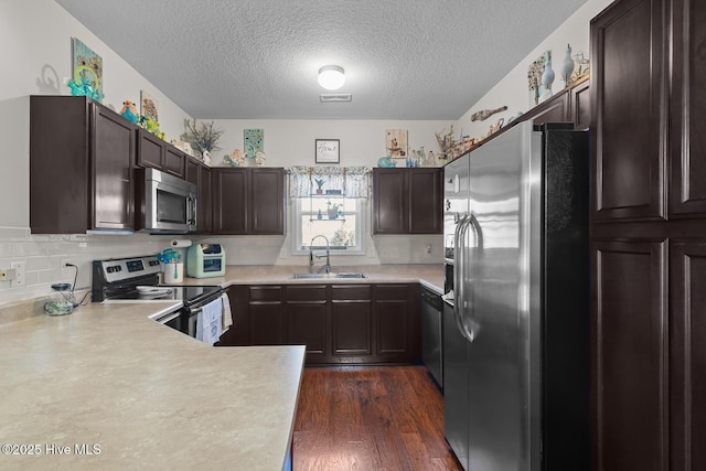 kitchen with sink, tasteful backsplash, dark hardwood / wood-style flooring, kitchen peninsula, and stainless steel appliances